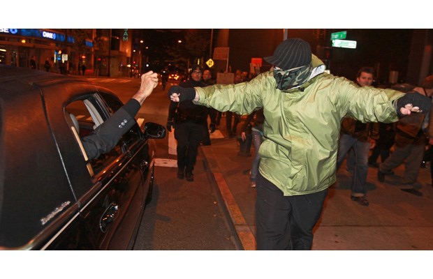 A man in a limo offered a fist bump to a masked protester, who took him up on the offer, Friday night, Oct. 14, 2011, in downtown Seattle, after Occupy Seattle demonstrators left Westlake Park for a march around downtown after 10 p.m. Protesters later returned to the park.
