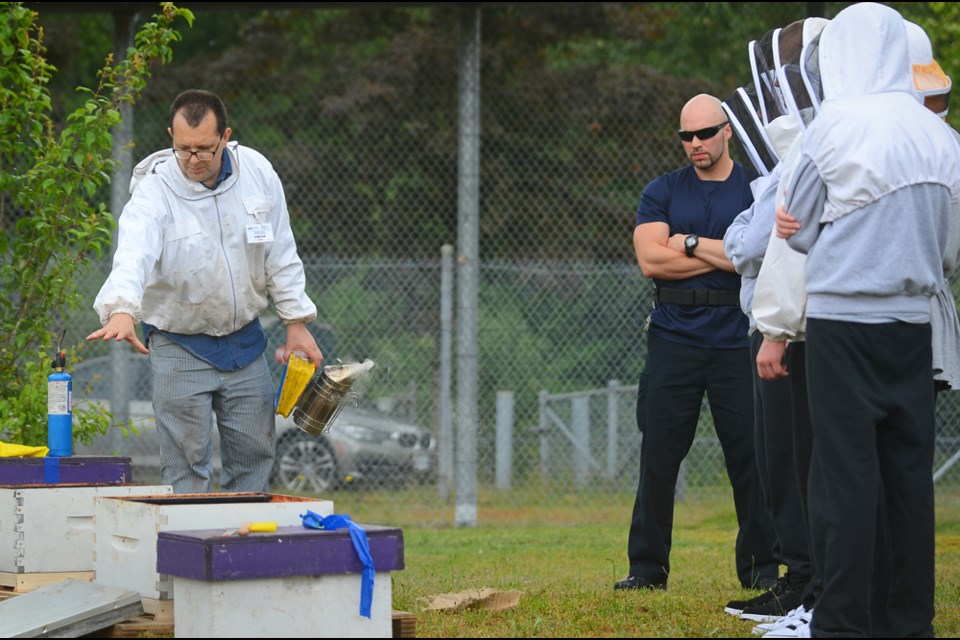 A youth correctional officer looks on as Burnaby teacher Brian Saunders talks about bees to prospective beekeeping students at the Burnaby Youth Custody Centre.