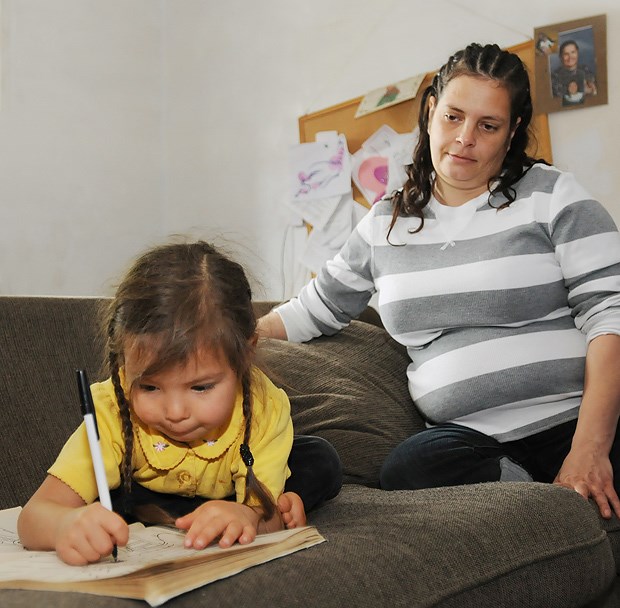 Gina Hawkins observes her daughter Mary drawing in a book before taking her to daycare.