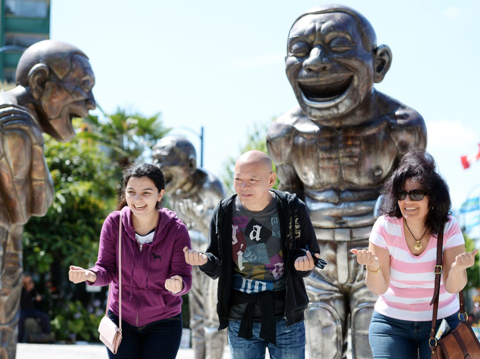 A-maze-ing Laughter, is made up of 14 giant smiling bronze men, all featuring artist Yue Minjun’s sm