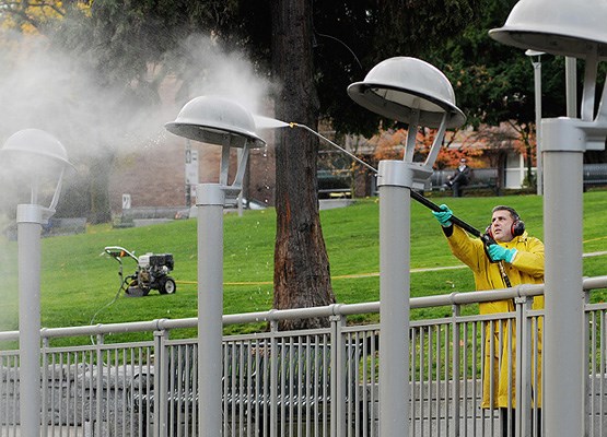 City worker Jason Harrington power washes the helmet light standards at Victory Square in preparation for Remembrance Day ceremonies.