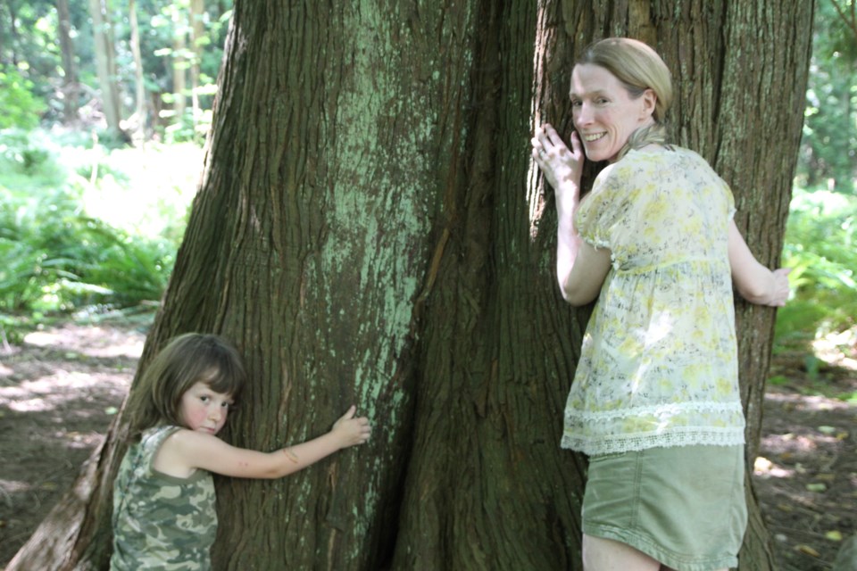 Catherine Barnum-Cummins and Luca hug Grandfather Tree, the tree that is the focal point of forest pre-school.