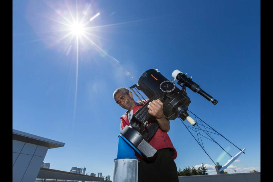 Astronomer Karun Thanjavur sets up a modified telescope -- it projects an image of the sun -- that will be used for viewing the Aug. 21 solar eclipse from the roof of the Bob Wright Building at the University of Victoria.