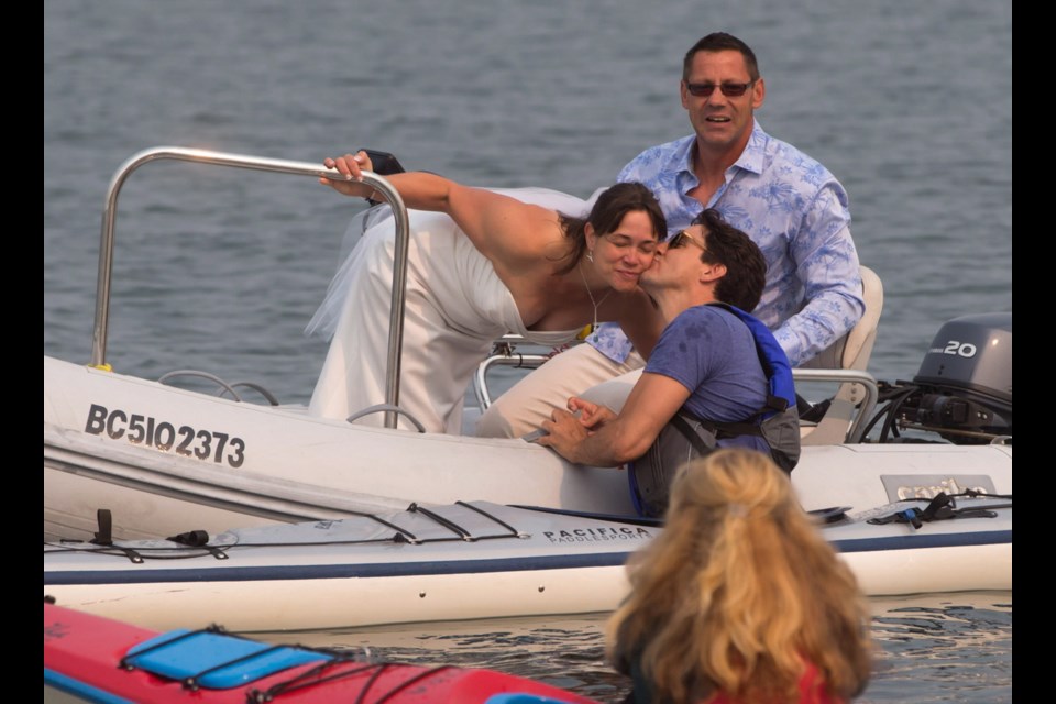 Prime Minister Justin Trudeau, front right, gives a kiss to new bride Michelle Gruetzner as her husband Heiner Gruetzner, back, watches after they came across Trudeau kayaking at Sidney Spit in the Gulf Islands National Park Reserve, while taking a boat to a wedding reception, east of Sidney on Saturday, Aug. 5, 2017. THE CANADIAN PRESS/Darryl Dyck