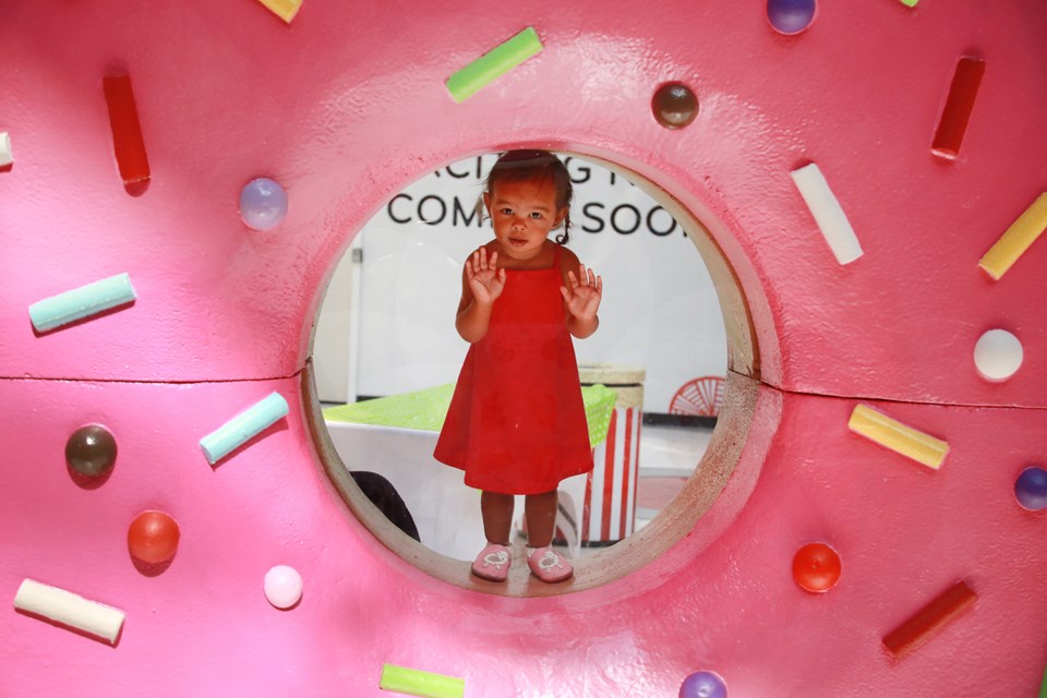 Two-year-old Zoë Tettevi stands inside giant doughnut at Metropolis Tasty Treats, an exhibition on now at Metropolis at Metrotown.