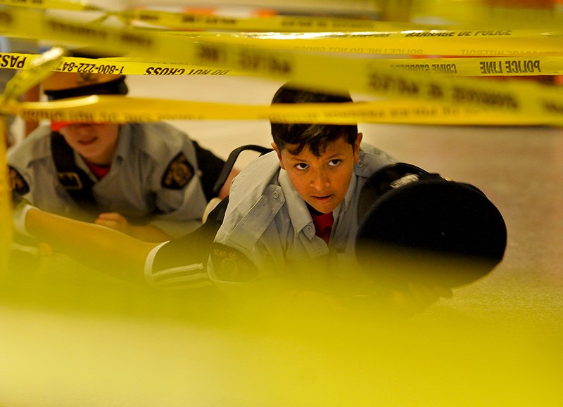 MARIO BARTEL/THE TRI-CITY NEWS
New recruits in the Coquitlam Junior Mountie Police Academy crawl through a maze of police tape during the uniform race Wednesday at the Poirier Sport and Leisure Complex. The week-long camp gives kids aged 9-15 a chance to experience police work like apprehending "bad guys," to investigating a crime scene to taking fingerprints. The camp is in its seventh year.