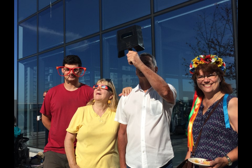 Coun. Lorrie Williams, in yellow, is joined by friends at an eclipse viewing party she held on the patio of the Anvil Centre Office Tower Monday morning.