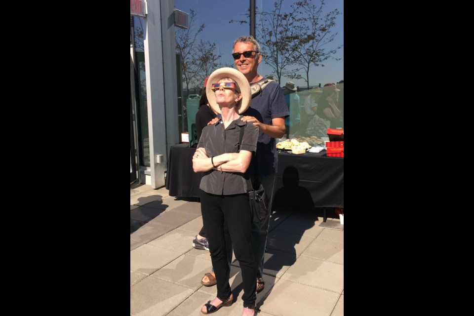 Community members, including Alison Kirkley and Rick Carswell, gathered at a rooftop patio at Anvil Centre on Monday morning for an eclipse viewing party hosted by Coun. Lorrie Williams.