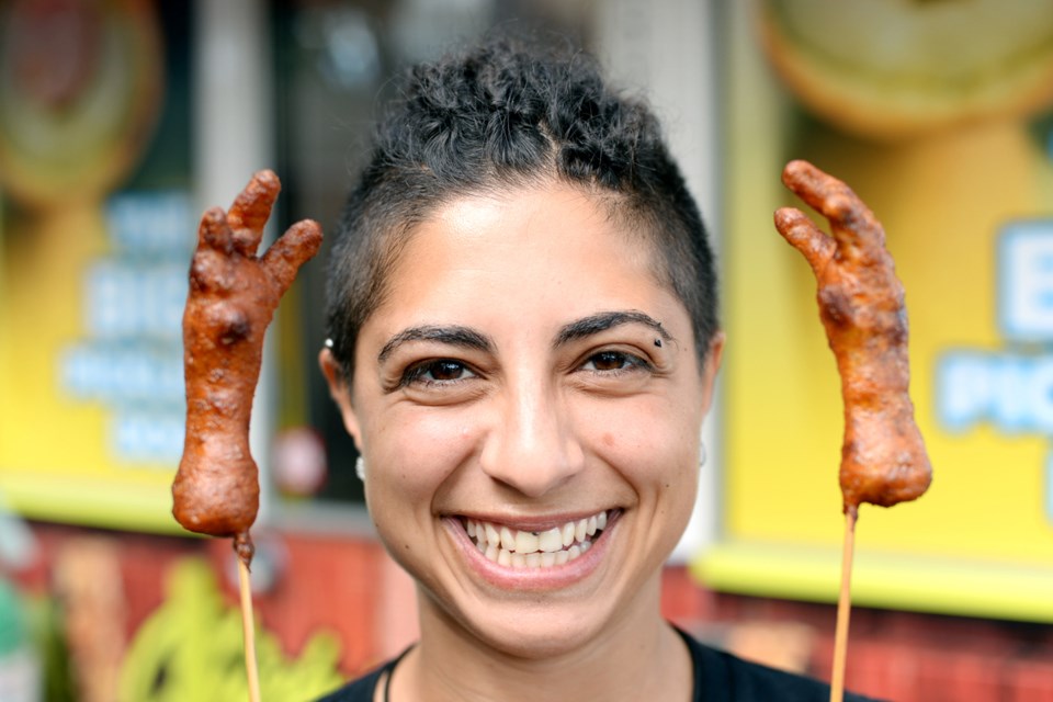 Carmen Saiad, manager of Chicky's Chicken, holds up some deep-fried chicken feet served on a stick. Photo Jennifer Gauthier