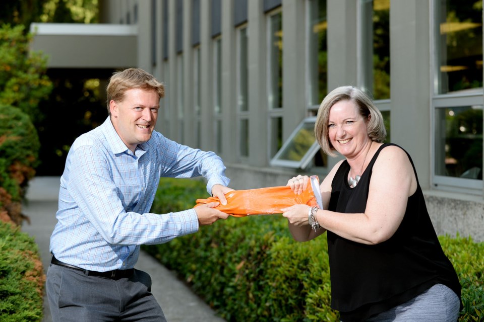 Mayor Jonathan Cote and Lori Mayhew, president of the New Westminster and District Labour Council, face off over a Hyacks-orange gauntlet in anticipation of the annual Hyacks Homecoming tug-of-war competition. Team Union has defeated Team City Hall for the past two years at the annual event, which returns as part of the Homecoming fun on Sept. 8 at Mercer Stadium.
