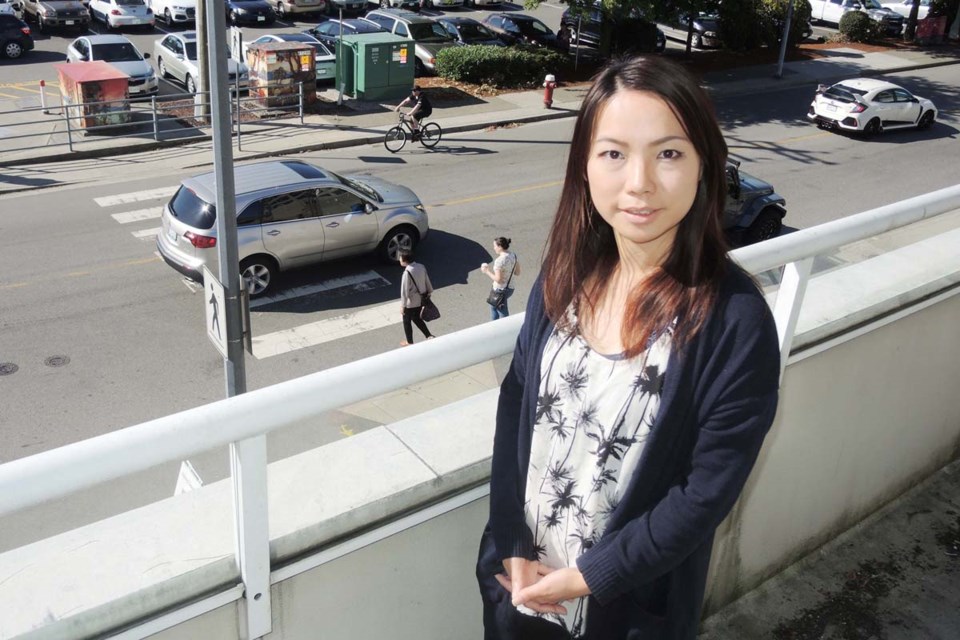 Angela Pong, an integrated media consultant at the Richmond News, looks down onto the crosswalk from the balcony of her second floor office on Ackroyd Road. Pong was almost hit by a car speeding through the crosswalk. She says there are too many distractions for drivers in the area. Photo by Alan Campbell/Richmond News