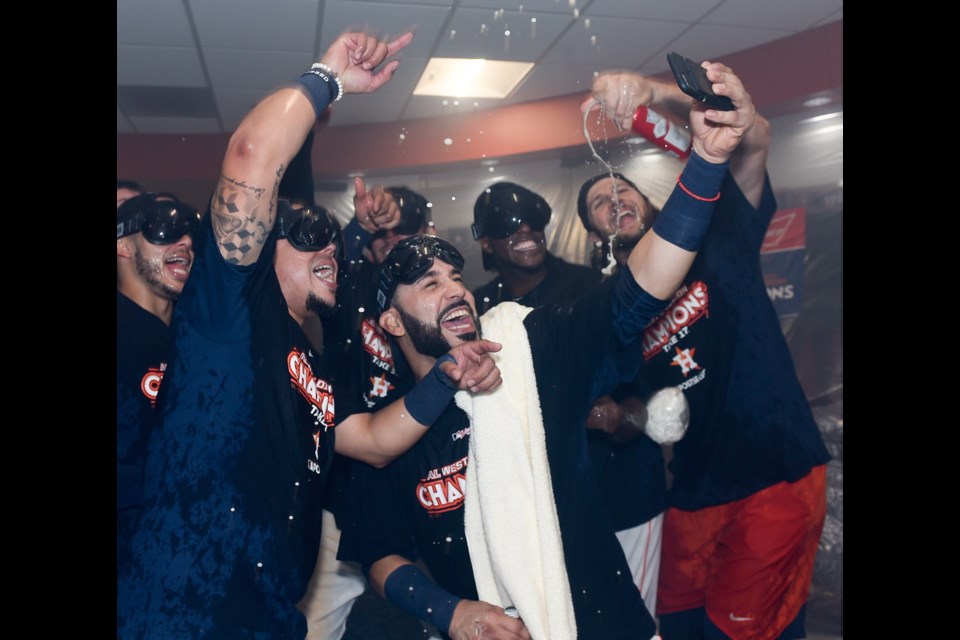Houston Astros' Marwin Gonzalez, centre, and Juan Centeno, left, celebrate after the team's win over the Seattle Mariners and the clinching of the AL West crown in a baseball game, Sunday in Houston.