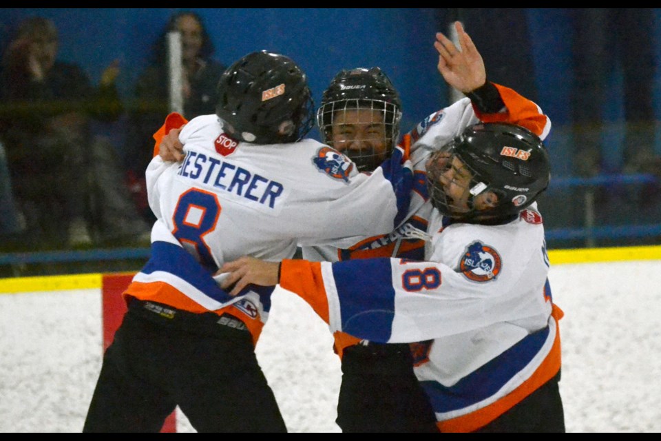 Seafair's Jaden Uy is mobbed by his teammates after scoring the game-winning shootout goal in the Bantam A1 championship game on Monday at the 15th annual Seafair Icebreaker Rep Hockey Tournament.
