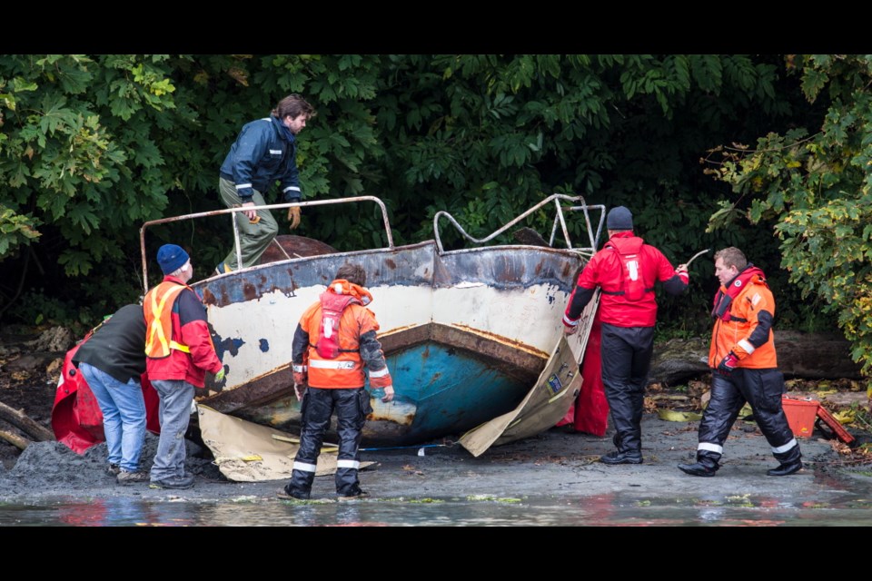 Tow crews prepare to remove a metal boat at Cadboro Bay beach on Saturday. "These boats are dangerous here," says Eric Dahli, chairman of the Cadboro Bay Residents Association.