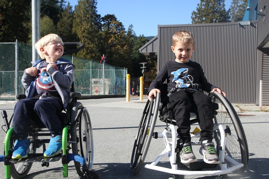 Matthew Honing, left, hangs out on the school basketball court with Jack, who enjoys scooting around in the wheelchair left at BICS by the organization Let's Play.