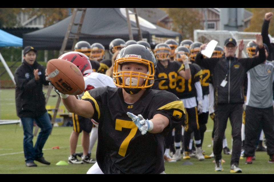 Reace Mok celebrates his first quarter touchdown with his teammates and coaches cheering him on, including Bill Haddow (right).