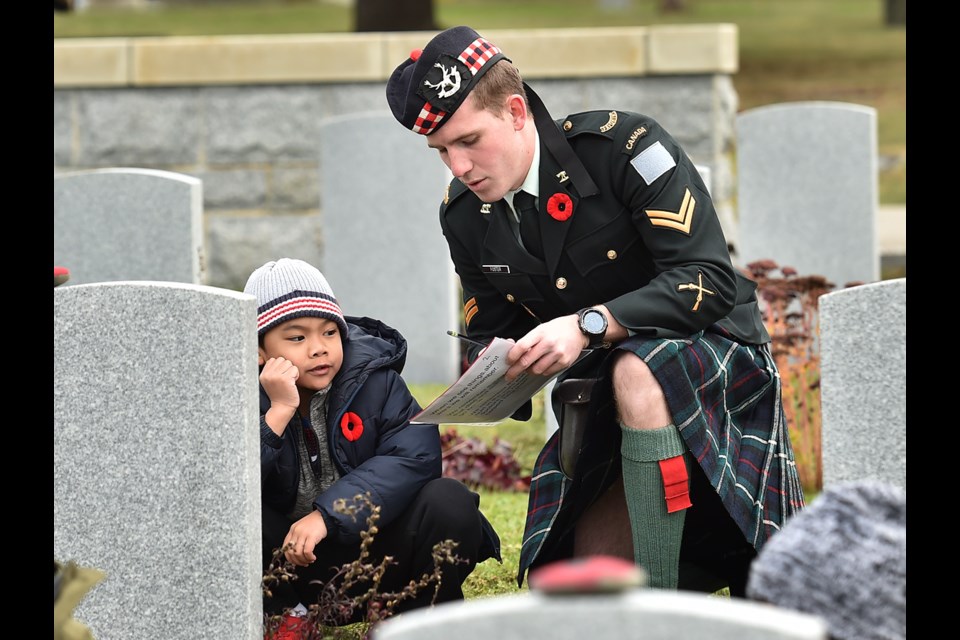 Students from St. Mary’s Catholic school and members of the Canadian Army and Air Force participated in the No Stone Left Alone ceremony at Mountain View Cemetery Tuesday morning. Pictured is Kristian Nicolas, 7, and Corporal Adam Foster, a Seaforth Highlander. Photo Dan Toulgoet