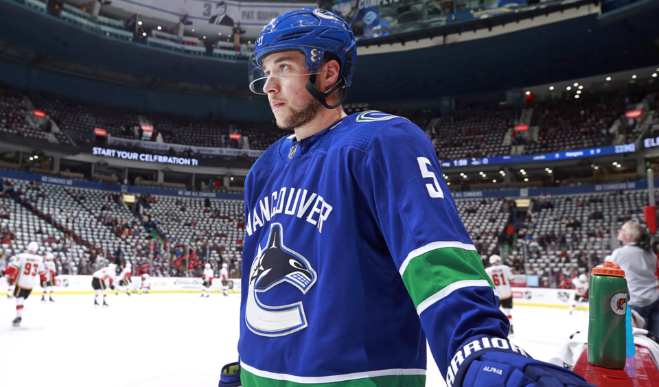 Derrick Pouliot stands at the bench before the Canucks face the Flames.