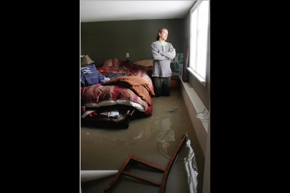 Christopher Olson stands in water up to his knees in the basement of his mother's house. The home, on Bowker Avenue in Oak Bay, flooded after a water main broke.