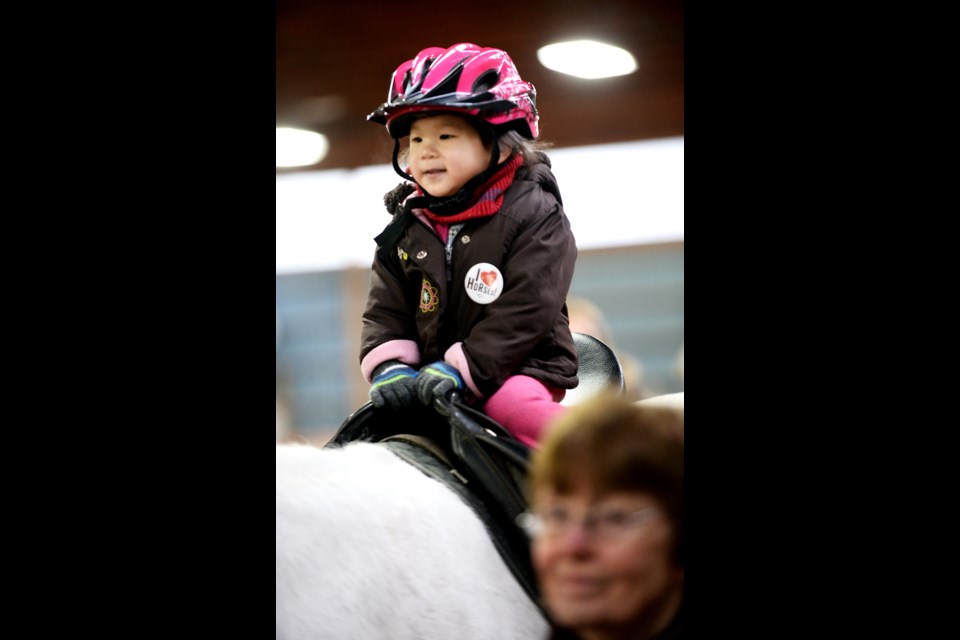Two-year-old Evangeline Chua rides a pony at the 16th annual Christmas with the horses.
