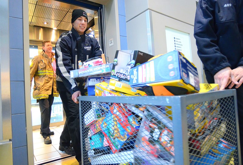 Burnaby firefighter David Parker, followed by colleague Matt Denton, rolls a shipment of toys destined for the Burnaby Community Services Christmas Bureau out of a Metropolis at Metrotown elevator.