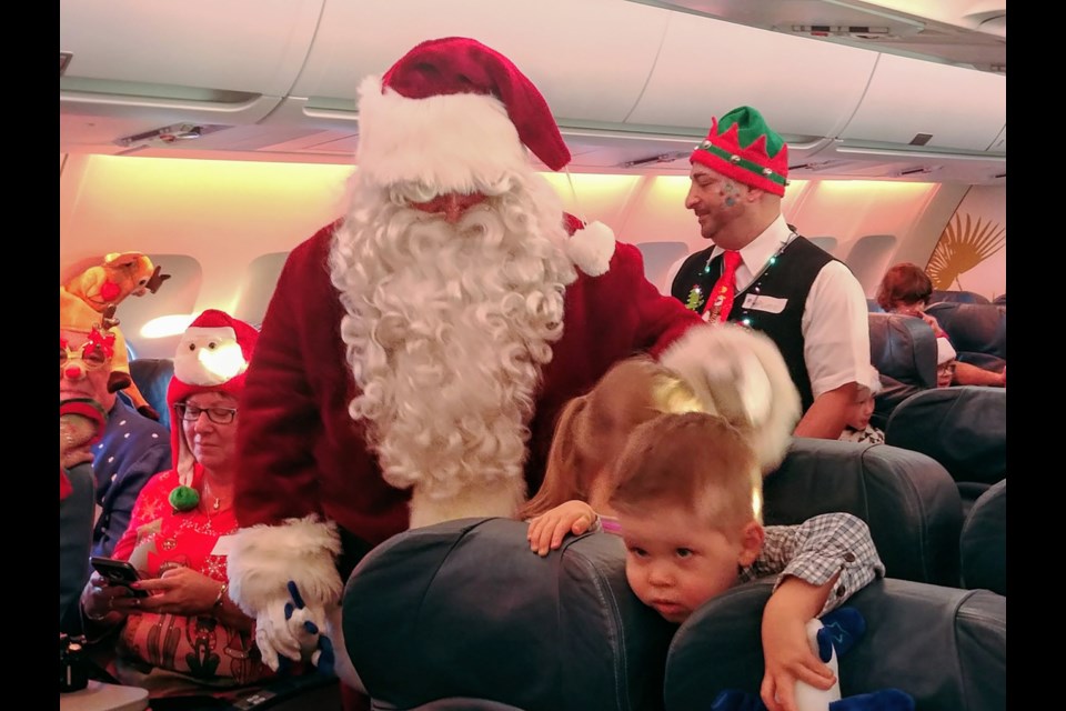 Santa handed out gifts and candy canes to children during an Air Transat flight to the "North Pole" with the Children's Wish Foundation Dec. 6. Photo Sandra Thomas