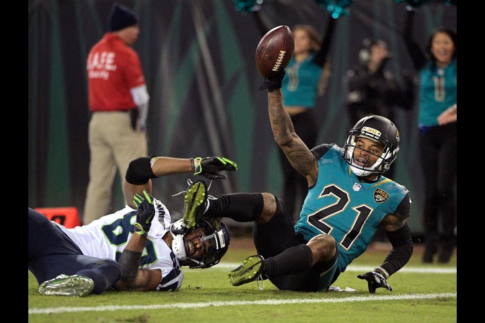 Jacksonville Jaguars cornerback A.J. Bouye (21) holds up the ball after he intercepted a pass in the end zone intended for Seattle Seahawks wide receiver Doug Baldwin, left, during the second half of Sunday's game in Jacksonville, Fla. Jacksonville won 30-24.