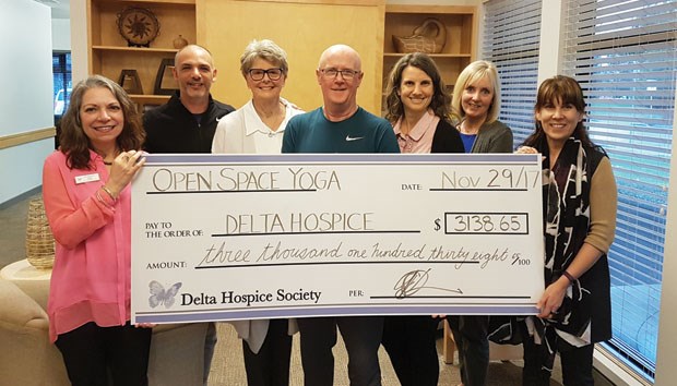 Open Space Yoga owner Gary Sylvester (middle) presents a cheque from the annual Shopping Day to the Delta Hospice Society.