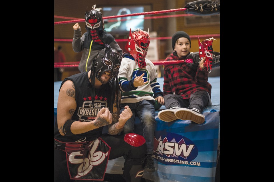 Pint-sized fans Asher Boulos, Oweynn Yarmush and Jeremy Hutchins (front to back) pose for a photo with one of the All Star Wrestling performers the most recent match at Totem Hall.