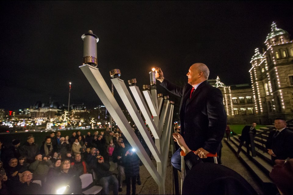 Premier John Horgan lights a menorah on the front steps of the B.C. legislature on Tuesday night. Dec. 12, 2017