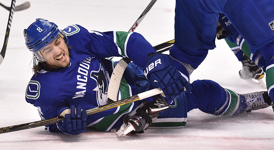 Chris Tanev grimaces as he falls to the ice for the Vancouver Canucks.