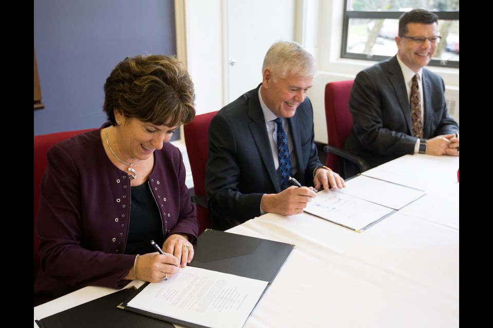 Camosun College president Sherri Bell signs the Education Victoria agreement with superintendent of School District 61 Piet Langstraat, centre, and Dave Eberwein of School District 63.