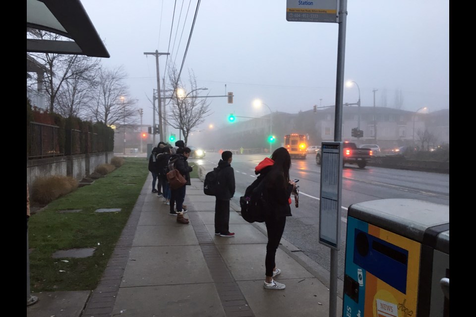 Wait for it: Students wait at Howes Street and Ewen Avenue for the bus to 22nd Street SkyTrain station and then to New Westminster Secondary School. School board trustee Mary Lalji would like to see the school district offer a bus service for students who live in Queensborough and attend the high school.