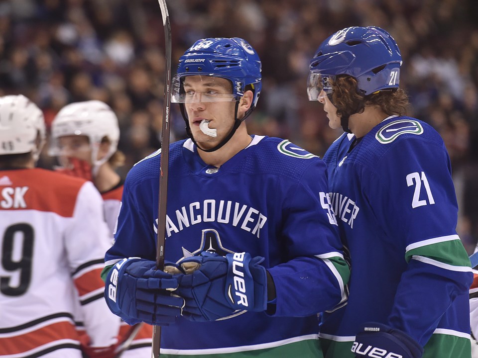 Bo Horvat stands with Loui Eriksson, mouth guard hanging out of his mouth.