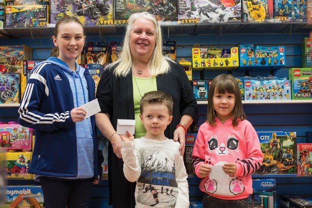Winners of the Optimist’s Christmas Colouring Contest receive their gift cards from Toys + Tech owner Marleen Flumerfelt. Addyson Murray, 11, Jon Martin, 5, Sienna Jefferson, 6, won their respective age divisons of the 28th annual contest.