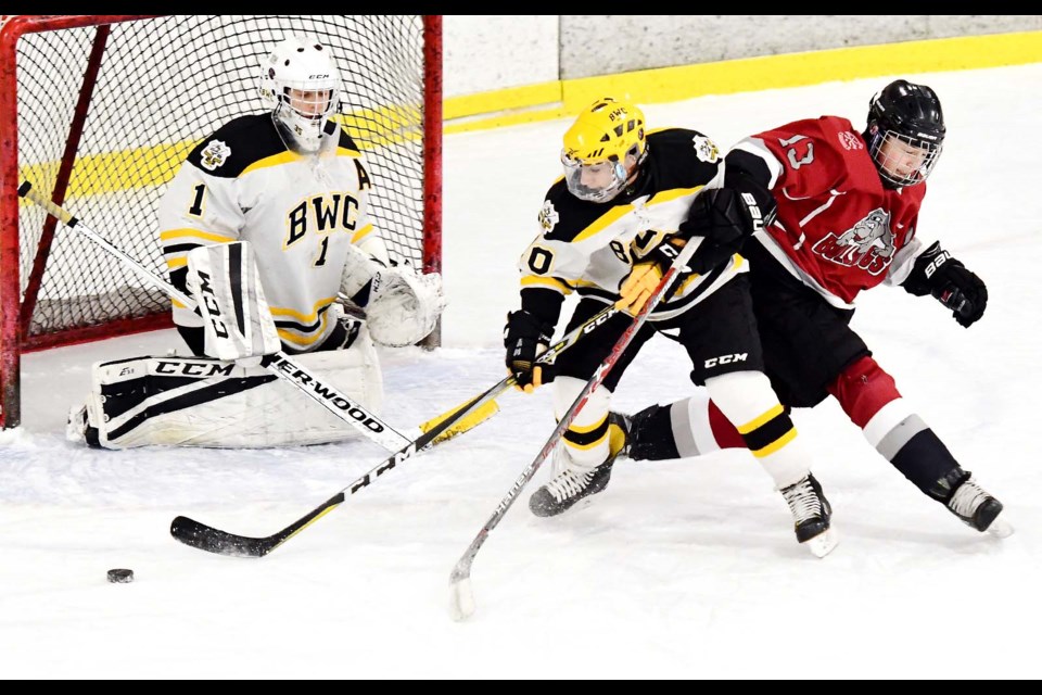 Burnaby Winter Club defenceman Manveer Bhachu, centre, clears the crease for goaltender Aiden Van Der Tas while under pressure from Burnaby minor Bulldogs’ Jared Hall during a bantam A hockey game last week.