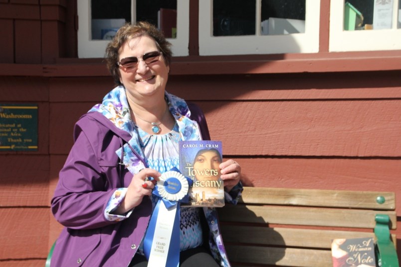 Carol Cram holds her first book, The Towers of Tuscany, published in 2014.