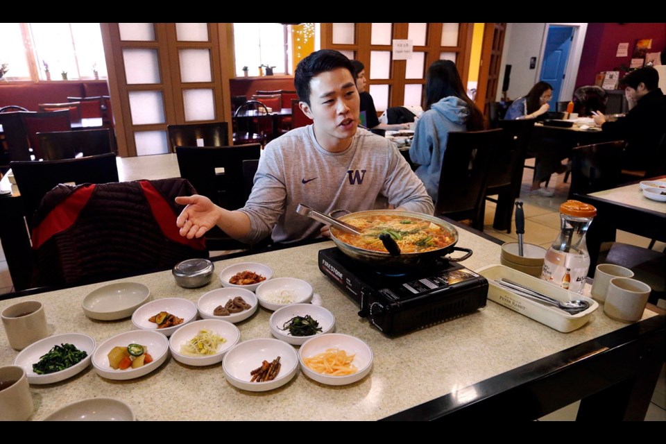 Server Young Kim discusses budae jjigae, or “army stew," simmering atop a heating plate at a Korean restaurant in Shoreline, Washington. Spam, trout and fried chicken are among South Korean dishes will look familiar to visitors at the 2018 Winter Games.