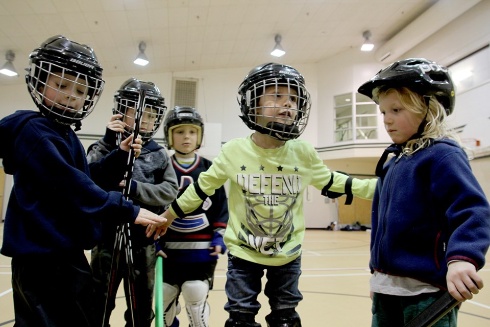 On the left, young hockey players crowd around coach Bristow in anticipation of their cheer. At right, Liam,