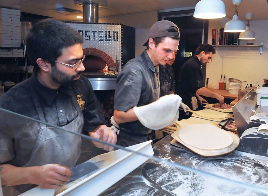 Head chef Aaron Lobo (left) and Aaron Slough spin pizza dough in the kitchen at Il Castello Pizzeria.