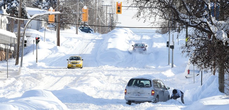 A common scene Thursday, a motorist stuck on 17th Avenue near Spruce Street. Residential snow clearing has begun.