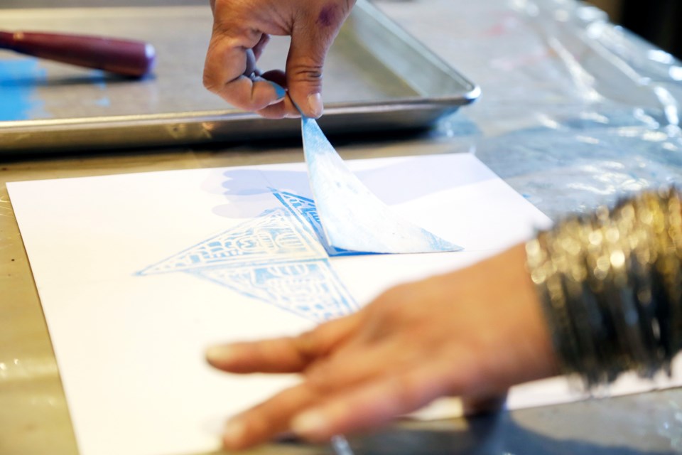 Gallery employee Mona Lochan works on a print while waiting for young artists to arrive.