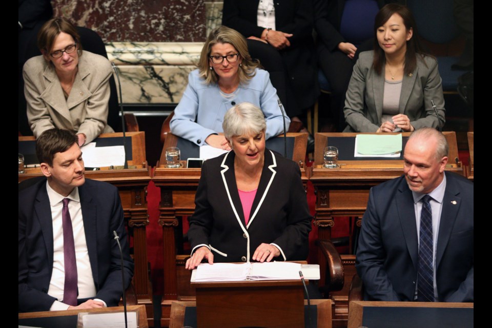 Attorney General David Eby, (left), and Premier John Horgan look on as Finance Minister Carole James delivers the budget speech from the legislative assembly at Legislature in Victoria, B.C., on Tuesday, February 20, 2018. THE CANADIAN PRESS/Chad Hipolito