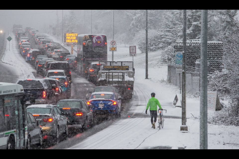 A cyclist walks along the Trans-Canada Highway near Uptown in Saanich on Wednesday, Feb. 21, 2018.