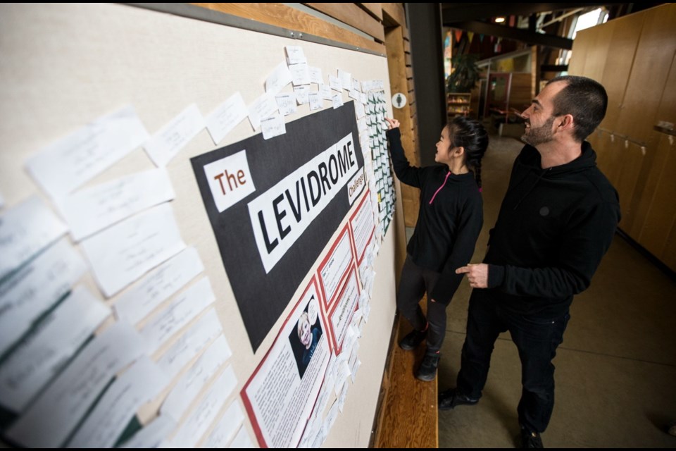 Teacher-librarian Travis Richey and student Ava Hong, 8, check out the latest contributions to the levidrome board at Strawberry Vale Elementary School in Saanich. Schools around the world have put up boards to promote Levi Budd’s word.