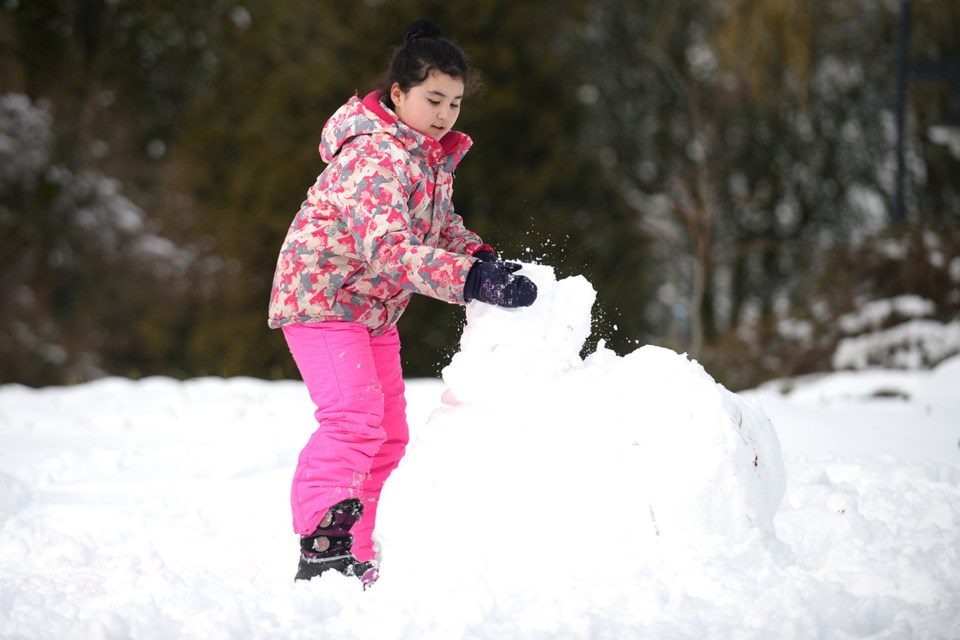 Nine-year-old Cathay Kattan builds a snowman in Deer Lake Park.