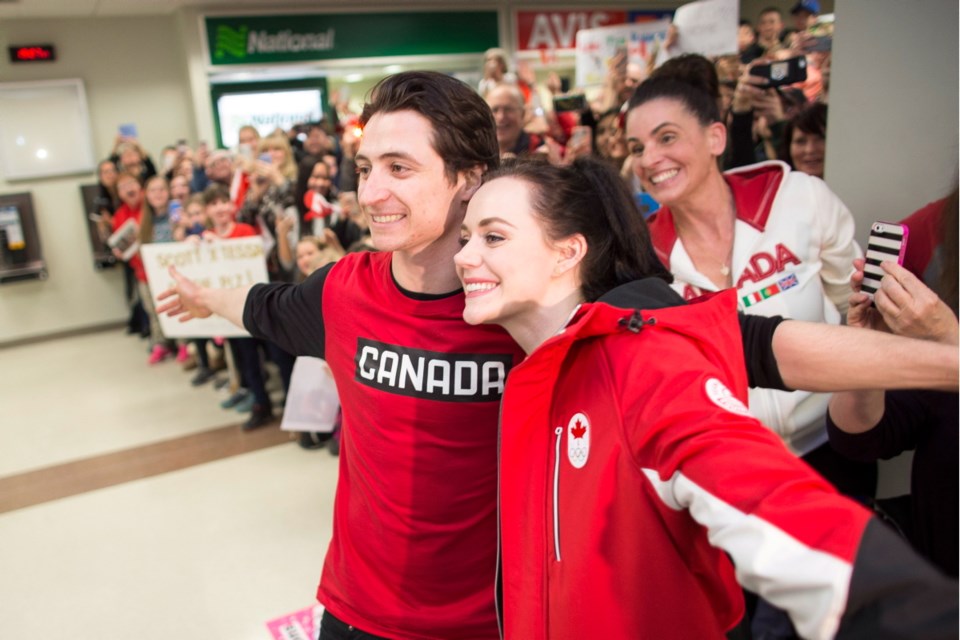 Olympic double gold medallists Scott Moir and Tessa Virtue pose for a photo with a crowd of well-wishers as they arrive home from the Olympics at the airport in London, Ontario, Monday, February 26, 2018.
