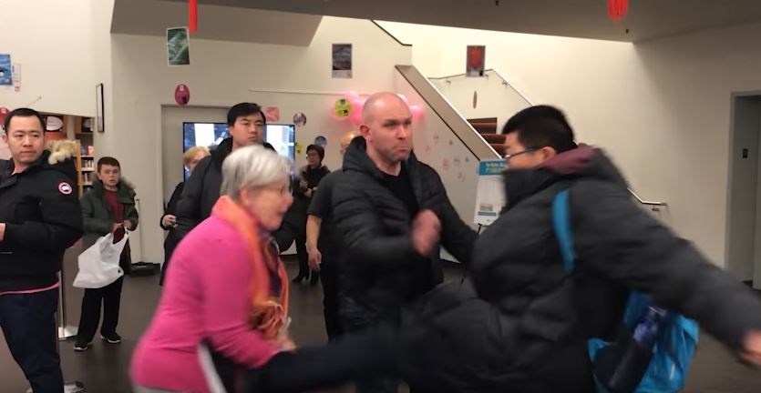 A video shows a man kicking a librarian at a public open house for temporary, modular housing in Richmond Wednesday evening. Screen grab.