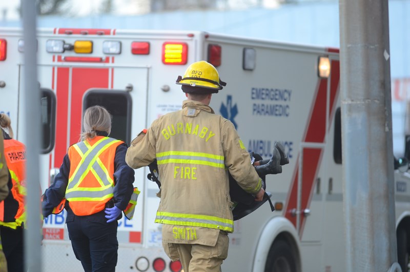 A Burnaby firefighter carries a young girl to a waiting ambulance in her car seat after a collision with an unmarked Vancouver Police Department vehicle in Burnaby Tuesday.