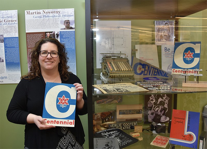 Candrina Bailey, executive director of Coquitlam Heritage, with an old Centennial secondary school annual in front of a display case showing mementoes from the high school, which is being demolished now that a new high school has opened.